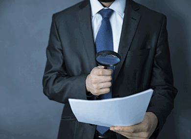 a man looking over papers with a magnifying glass